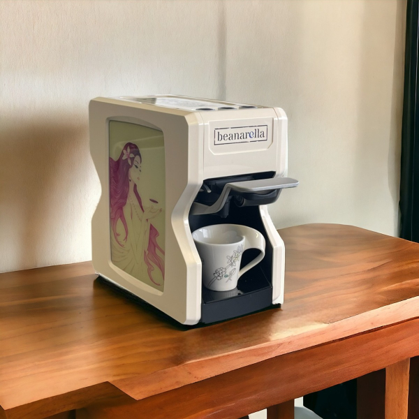 Machine à café Nori blanche Édition Spéciale - Lady Coffee, compatible avec des capsules compostables et des dosettes. Vue latérale avec une œuvre d'art représentant une femme avec une tasse de café. Parfait pour une préparation de café écologique.
