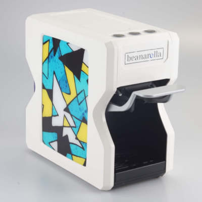 Weisse beanarella Nori Kaffeemaschine mit einem dynamischen, geometrischen Muster in Blau und Gelb – frisch und trendig