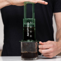 AeroPress Coffee Maker - Clear Green en cours d'utilisation pour presser un café dans une tasse.


