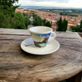 Tasse à espresso Aquarelli avec un motif de lac et de paysage sur une table en bois dans un environnement méditerranéen.