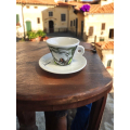Tasse à café Aquarelli avec un motif de lys calla sur une table en bois dans un décor italien.



