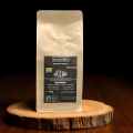 espresso bio beanarella Espresso Bolivia, grains entiers, certifié Fairtrade, sac sur tranche de bois devant fond sombre
