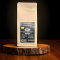 espresso bio beanarella Espresso Indonesia, grains entiers, certifié Fairtrade, sac sur tranche de bois devant fond sombre
