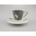 Monochrome Liberty Espressotasse mit einem Gesicht im Jugendstil auf weißer Untertasse, verbindet traditionelle Motive mit modernem Stil.