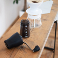 Hario Ceramic Coffee Mill Mini-Slim Plus, auseinandergebaut, mit einem Pour-Over-Set auf einem Holztisch.

