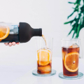 Bouteille Hario Cold Brew Coffee Filter servant du café infusé à froid avec des tranches d’orange dans deux verres.


