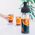 Bouteille Hario Cold Brew Coffee Filter, 650 ml, avec des tranches d’orange et du café infusé à froid, présentée avec plusieurs verres.



