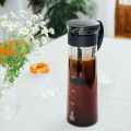 Hario Mizudashi Cold Brew Coffee Pot, rempli de café infusé à froid, sur une table dressée avec des fleurs.


