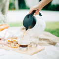 Hario V60 carafe blanche versant du café chaud dans une tasse, idéale pour les pique-niques.


