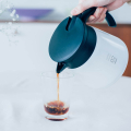 Carafe Hario V60 isolée, montrée dans une cuisine moderne avec d'autres accessoires de café.


