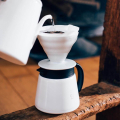 Hario V60 carafe blanche utilisée avec un filtre pour une extraction parfaite du café.


