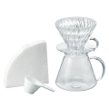 Kit Hario V60 Glass Brewing avec dripper, serveur, filtres en papier et cuillère doseuse sur un fond clair.



