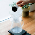 Dripper Hario V60 avec café moulu, présenté sur une balance de cuisine.


