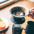 Nahaufnahme des Hario V60 Metal Drippers mit frisch gemahlenem Kaffee – Spiralrippen und Kegelform
