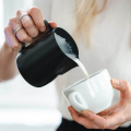 Rhinowares Stealth Milchkännchen 600 ml in Schwarz – Milch wird in eine weisse Tasse gegossen