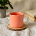 Tasse en porcelaine couleur saumon 340 ml sur un dessous de verre en bois – vaisselle élégante pour café ou thé