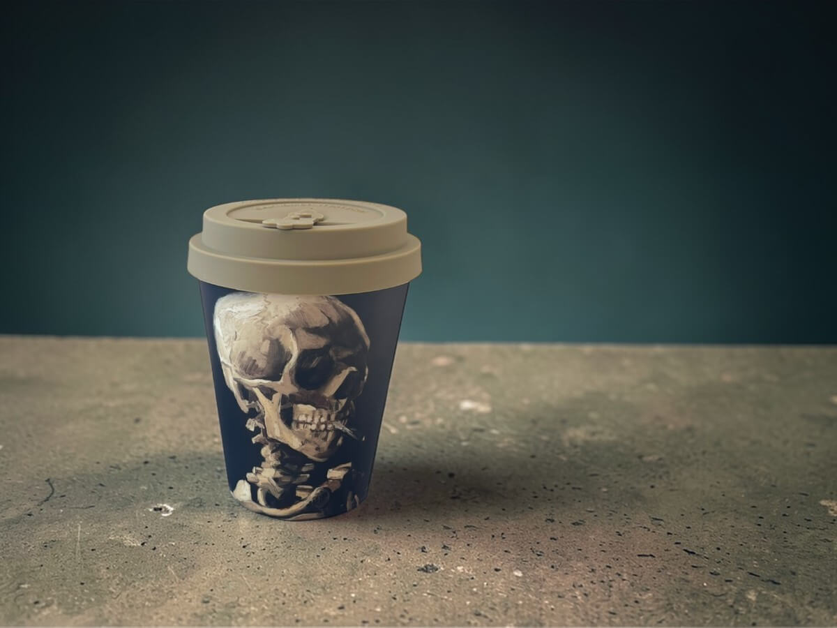 Ecoffee Cup Skull of a Skeleton Van Gogh Museum bicchiere da caffè 350ml con motivo teschio su superficie in cemento davanti a sfondo petrolio scuro in illuminazione studio atmosferica