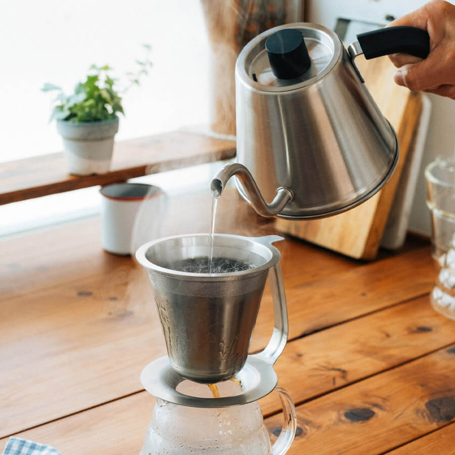 Filterkaffee von Hand mit dem Hario V60 Filterhalter – heisses Wasser wird aus dem Schwanenhalskessel aufgegossen.
