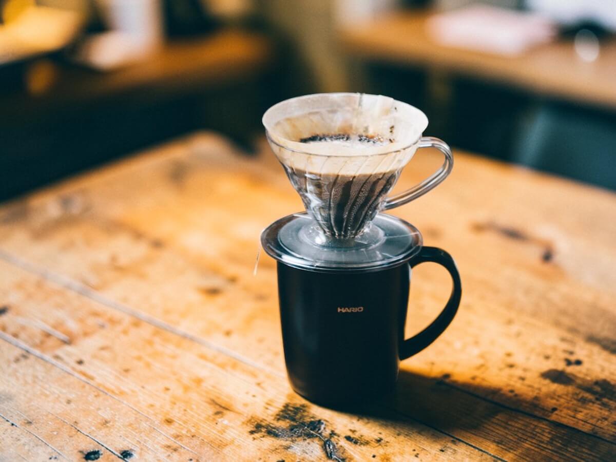 Hario heat retention mug with lid 300 ml black with glass manual dripper during coffee brewing on wooden table