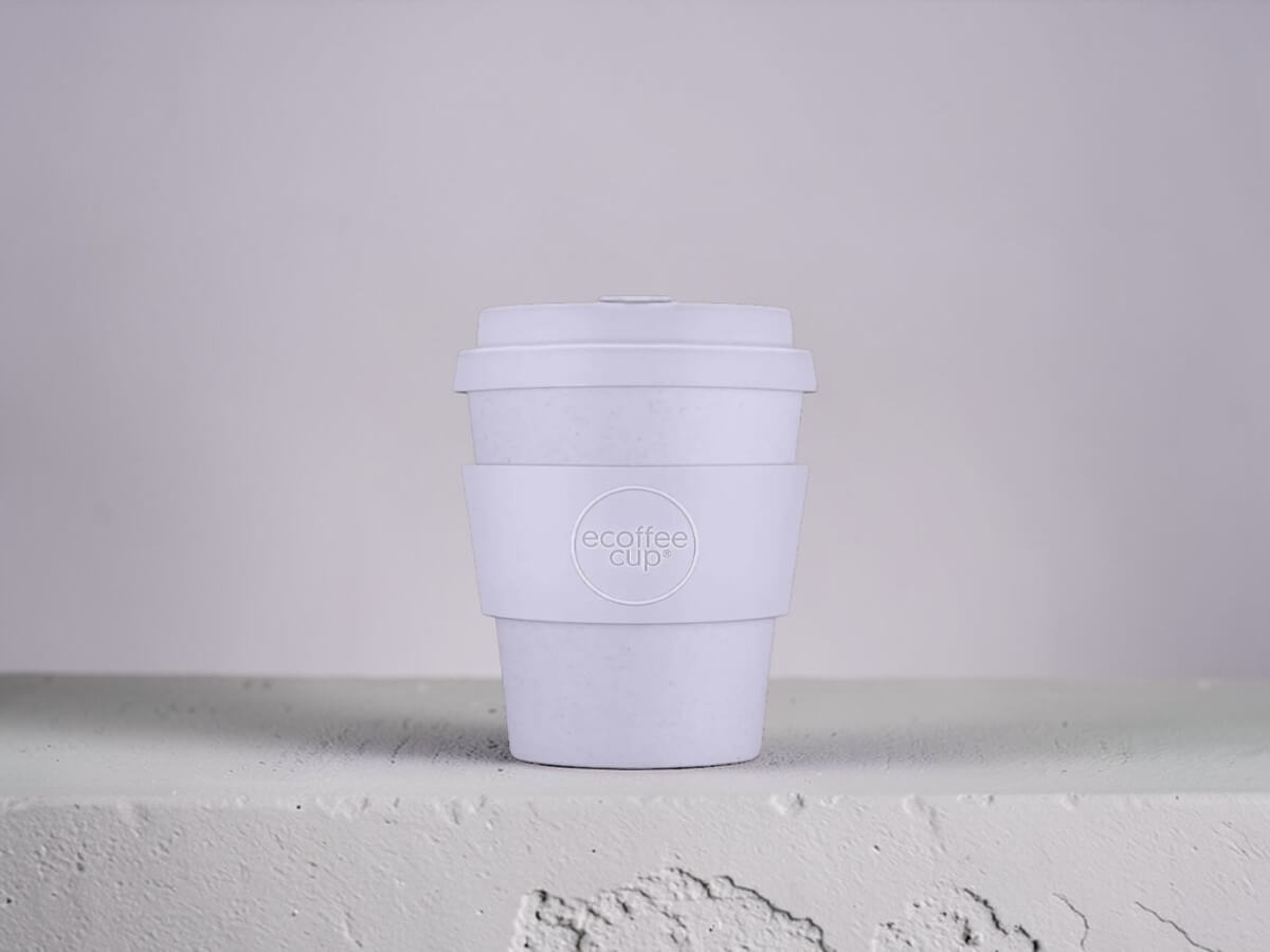 Coffee cup PLA 240ml Glittertind in white on plastered concrete wall with textured surface in minimalist product photography with soft daylight