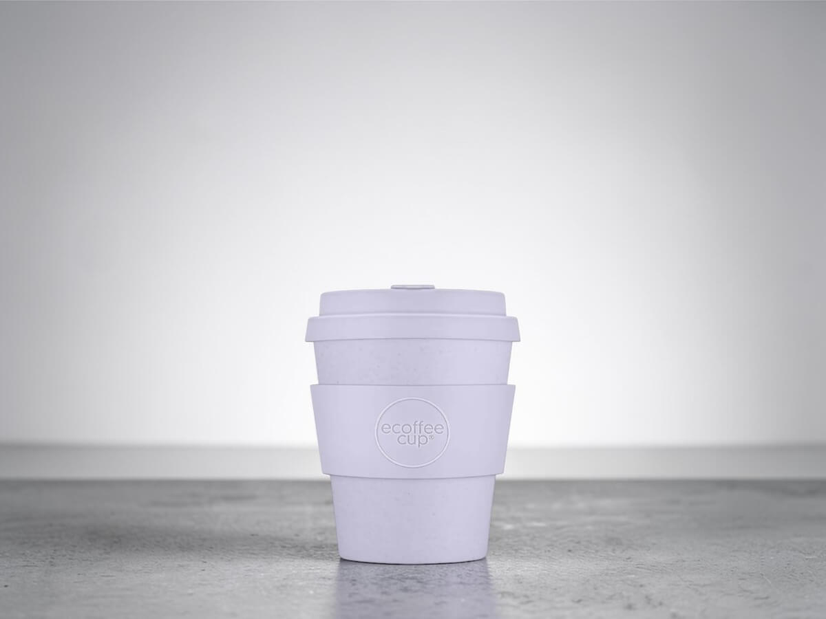 Coffee cup PLA 240ml Glittertind in white on smooth concrete surface with soft studio lighting and neutral grey background in purist product photography