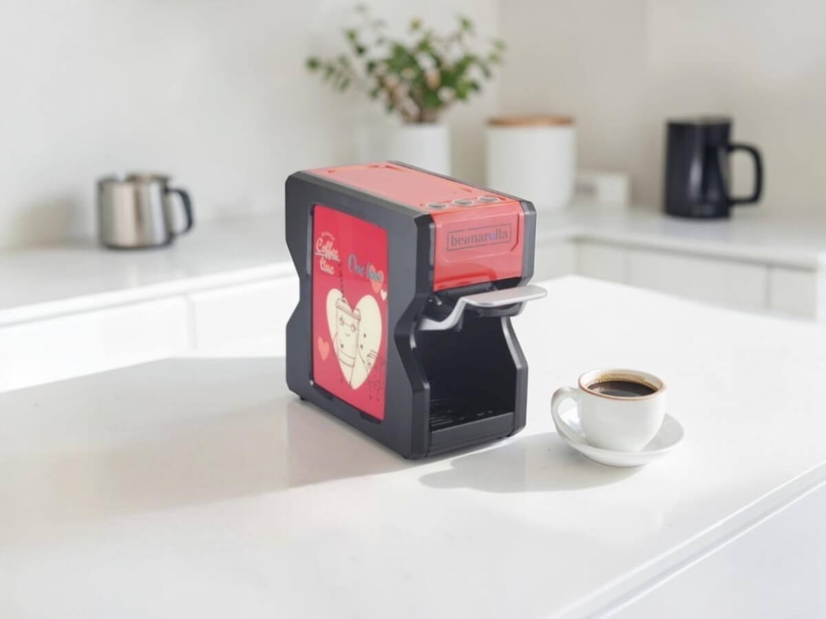 Customizable red beanarella Nori coffee machine with a One Love heart motif in a modern kitchen next to a cup of coffee