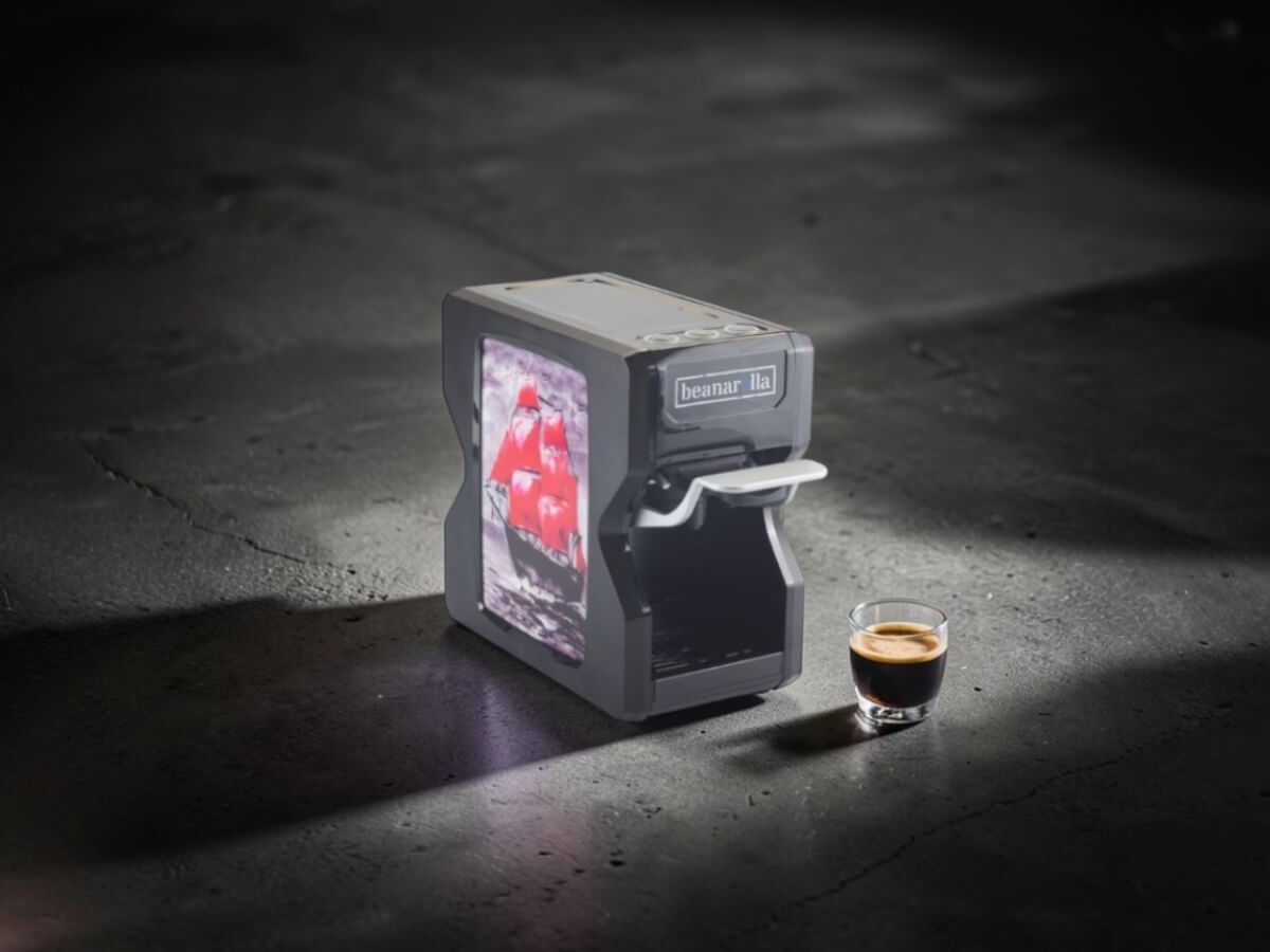 Customizable black beanarella Nori coffee machine with a red sailing ship motif next to a freshly brewed espresso