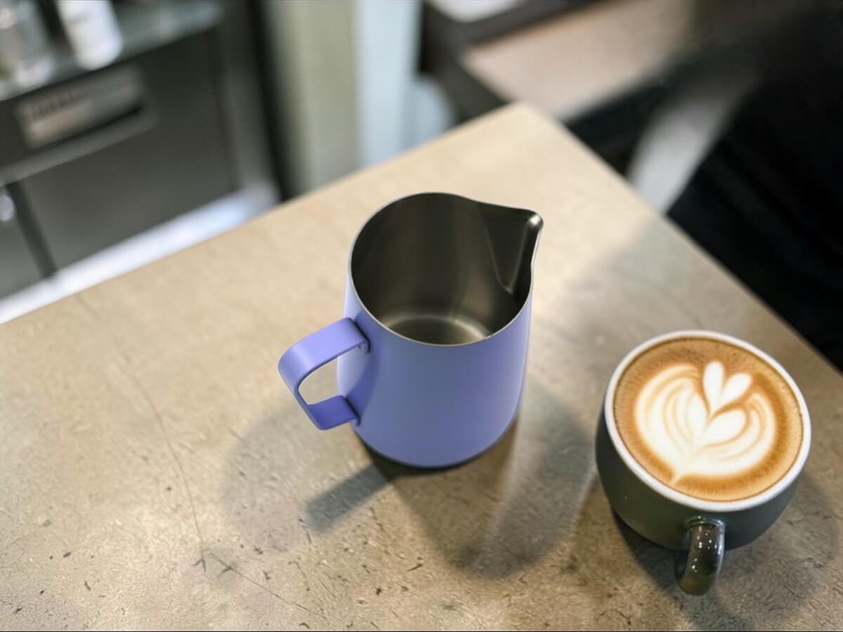 Rhino Classic Milchkanne 450ml in Lavender neben Cappuccino mit Latte Art auf Cafétisch