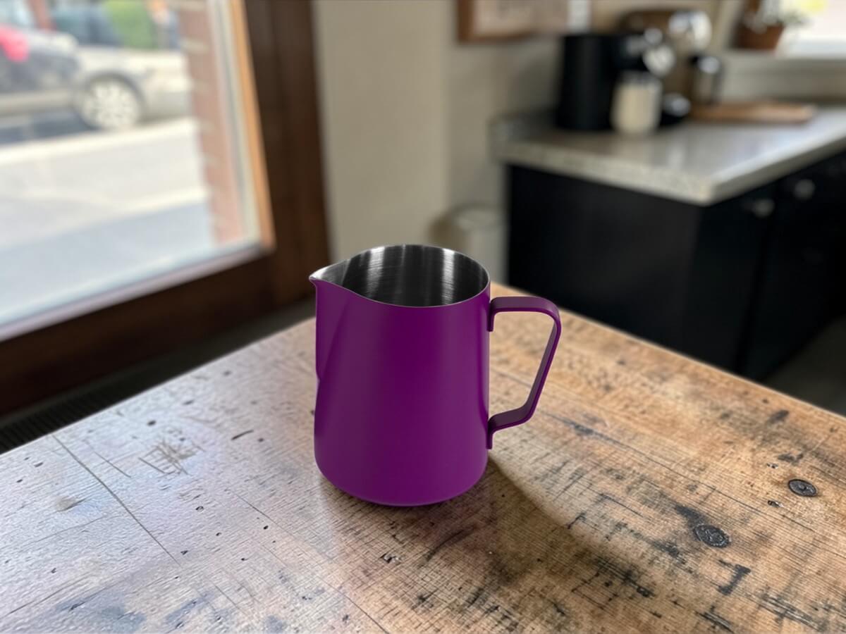 Rhino Classic Milchkanne 450ml in Vivid Plum auf rustikalem Holztisch am Fenster mit Kaffeemaschine im Hintergrund