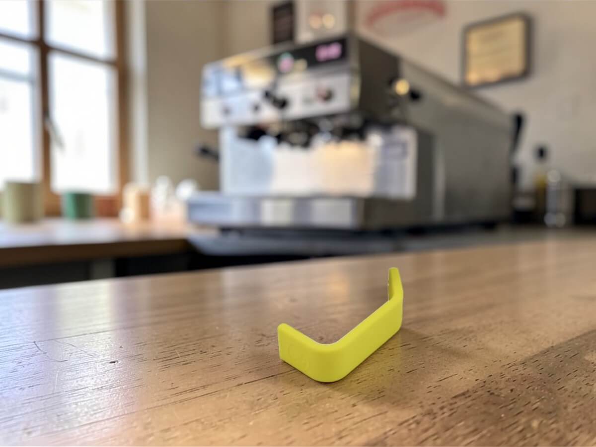 Rhino Yellow Silikon Griffüberzug 32oz auf Holztisch mit Espressomaschine im Hintergrund