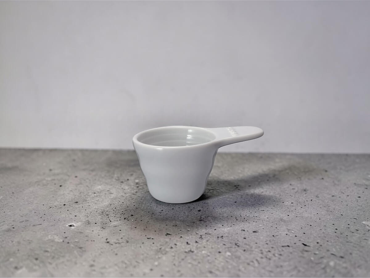 V60 Messlöffel 12g aus Keramik in Weiß als Produktfoto auf Betonoberfläche
